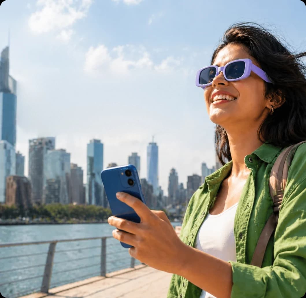Smiling traveler holding her phone by a city waterfront
