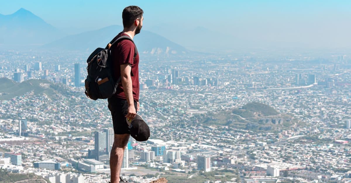 Traveler standing on a rocky overlook gazing at Monterrey's expansive and scenic urban cityscape below