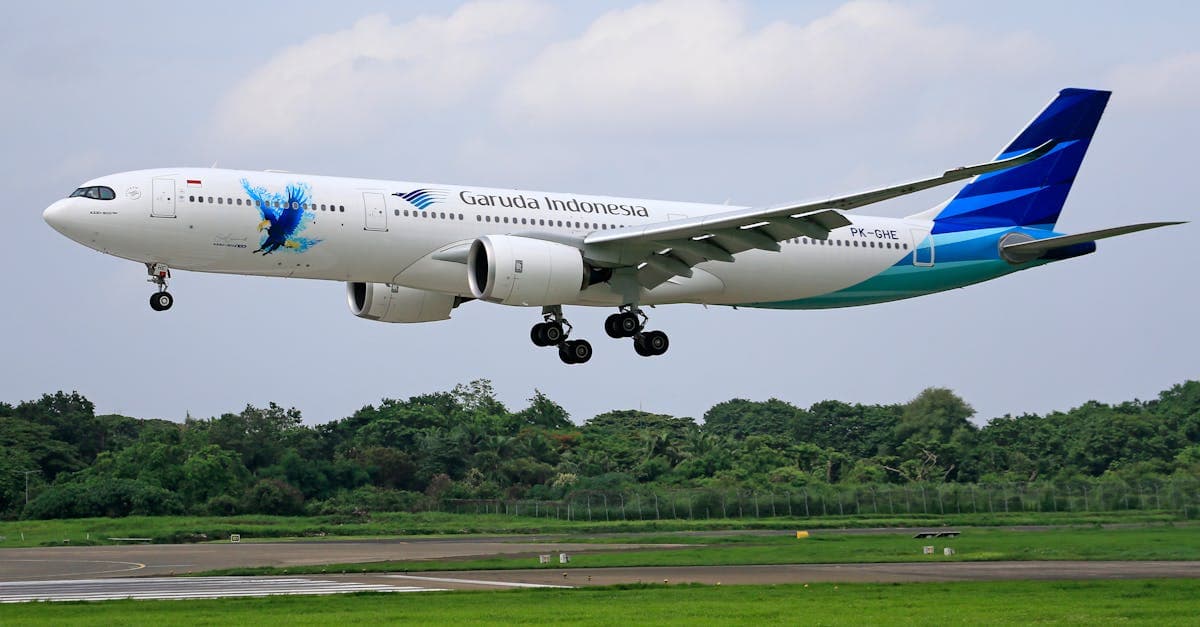 Garuda Indonesia Airbus A330 aircraft landing on a runway surrounded by greenery.