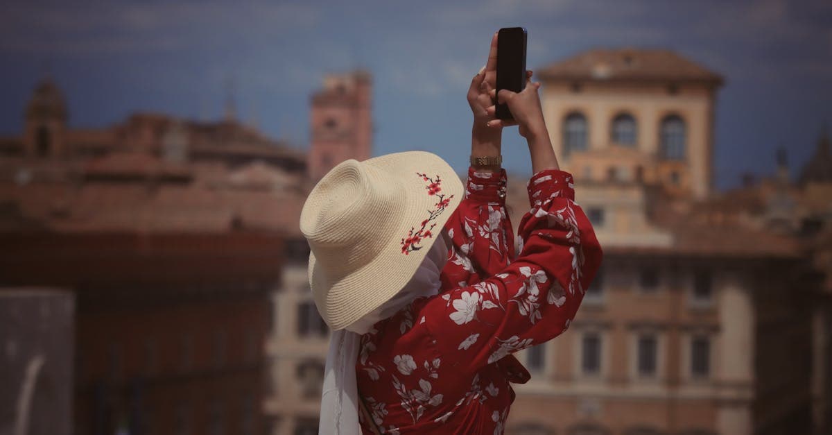 Donna in abito floreale e cappello fotografa una città europea con lo smartphone usando la migliore sim solo dati