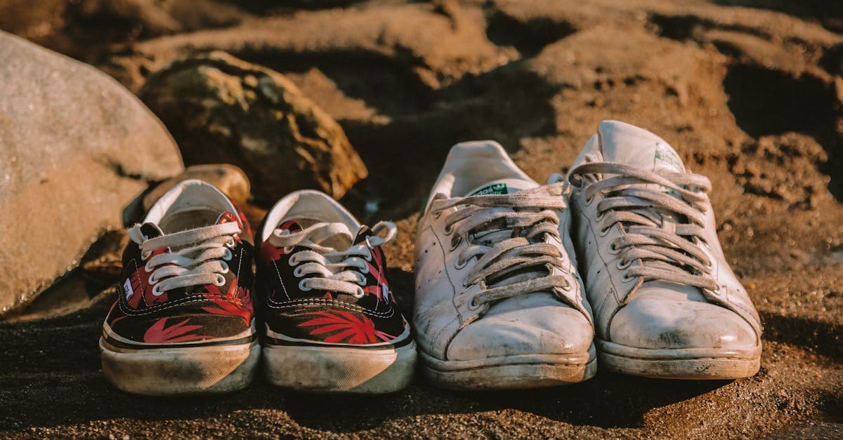 Worn sneakers resting on a sandy beach, a practical footwear choice for any travel packing list.