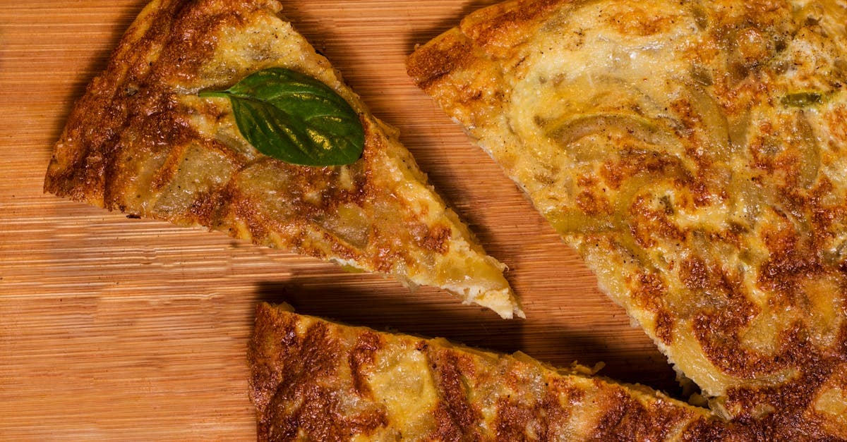 Sliced tortilla española on a wooden board garnished with basil, a classic Spanish tapa worth trying