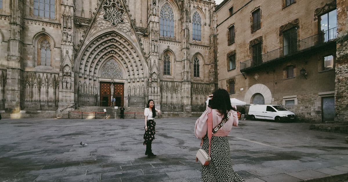 Twee vrouwen fotograferen de gotische gevel van de Barcelona Kathedraal tijdens een verblijf in de stad.