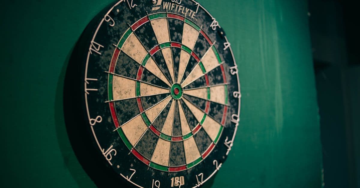 Abgenutztes Dartboard an grüner Wand als Symbol für den Dartsport rund um die Weltmeisterschaft.