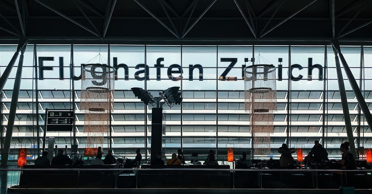 Reisende mit Gepäck in einem modernen Flughafen-Terminal vor dem Flug zum Kreta Flughafen Heraklion.