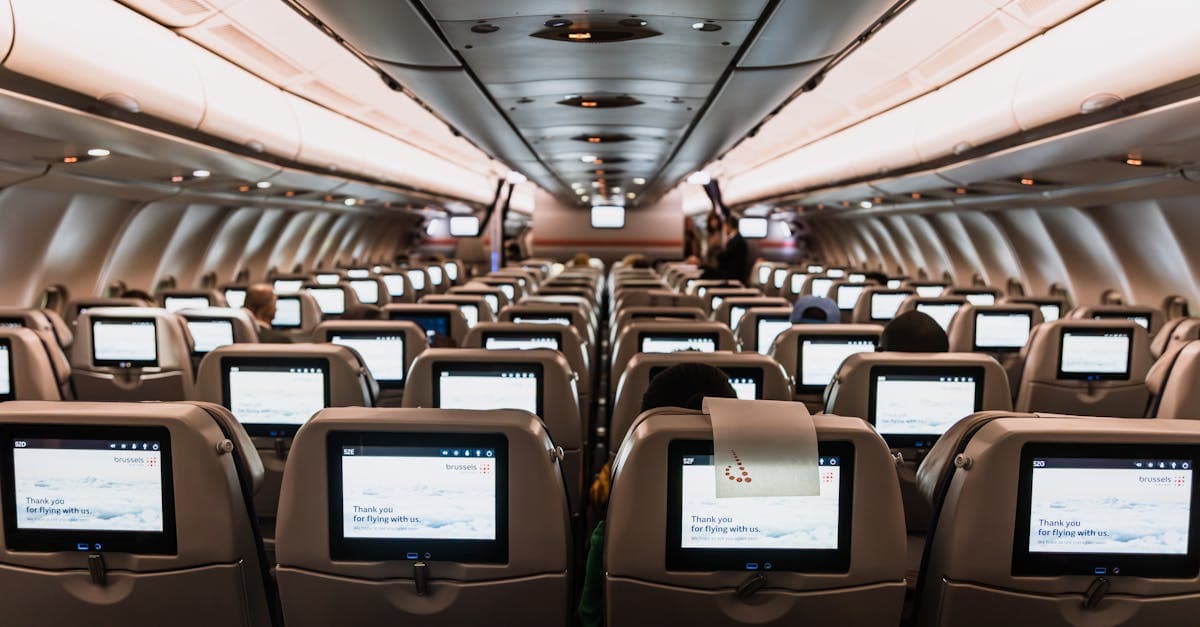 Komfortables Flugzeugkabinen-Interieur mit Unterhaltungsbildschirmen – separate Tickets bei Google Flights buchen