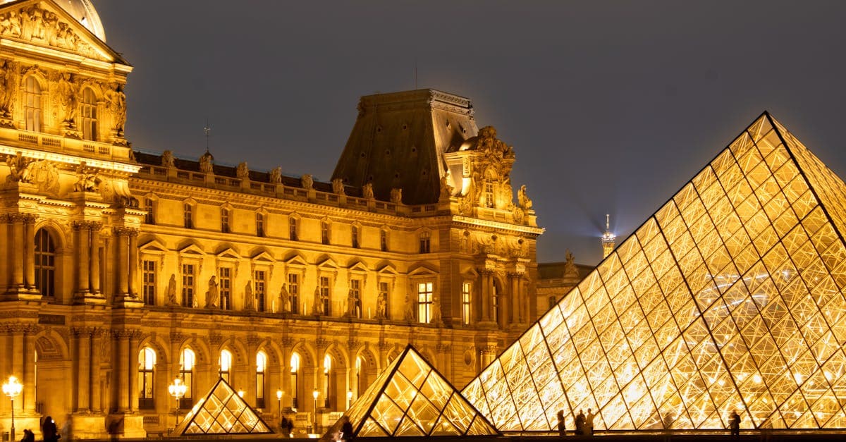 The Louvre Pyramid illuminated at night in Paris, near the city's best shops for must-buy Parisian souvenirs
