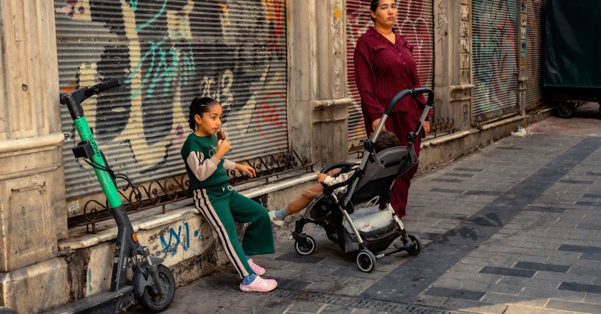 Mum and children eating ice cream beside vibrant urban graffiti during a relaxed city-break afternoon