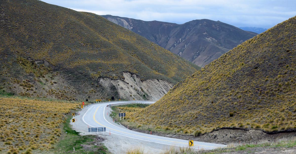 Winding road through rugged Otago mountains, perfect destination for open-jaw budget flights New Zealand.![image
