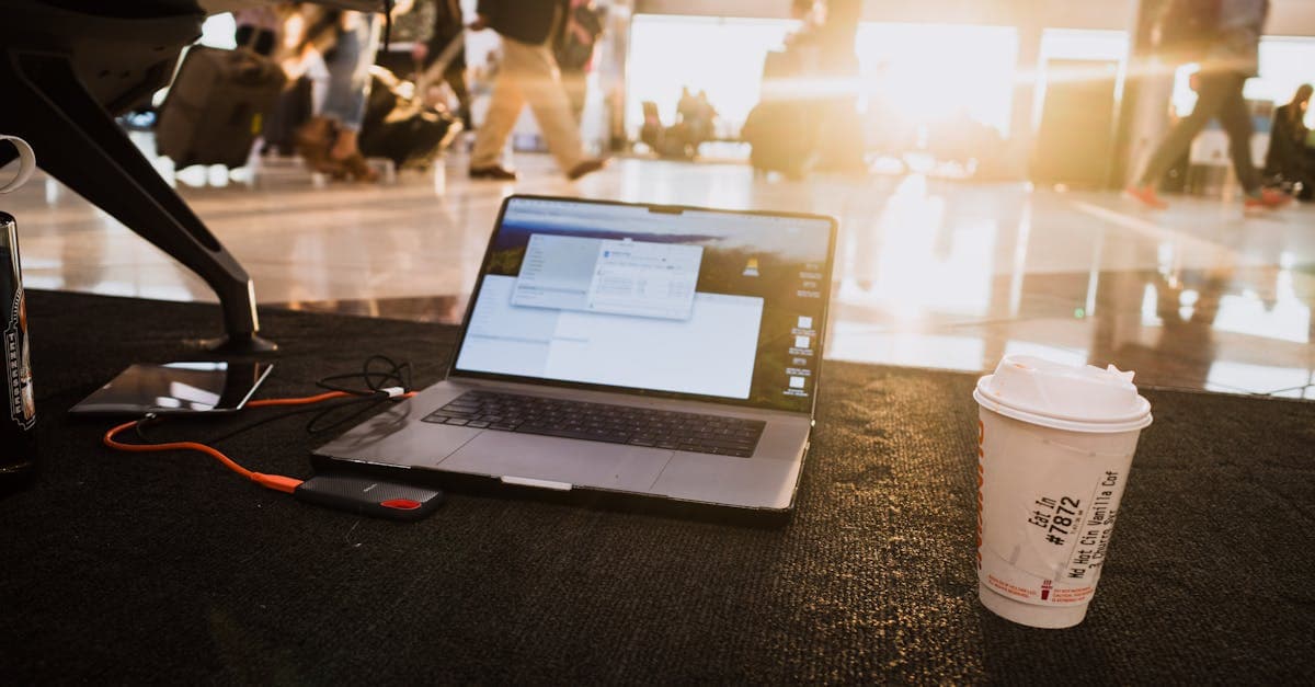 Laptop and coffee on an airport floor highlighting portable wifi hotspot signal placement and heat throttling