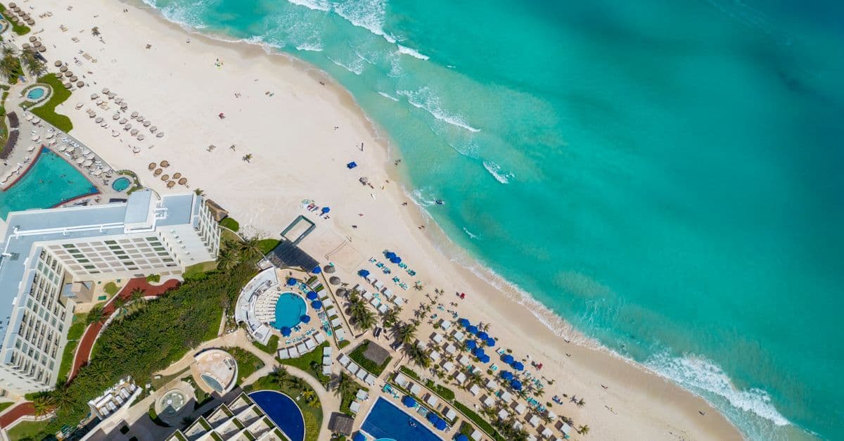 Aerial view of Cancun's sandy beach and turquoise waters, ideal for budget travelers visiting during off-peak months.