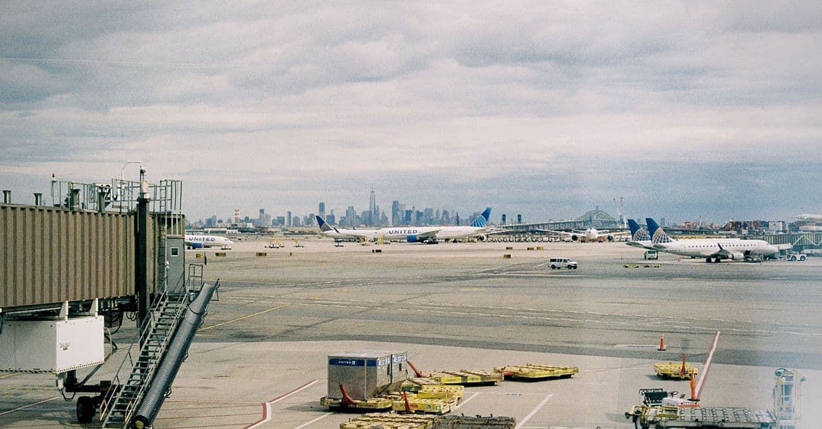 Aerei sul piazzale di un aeroporto, con lo skyline di New York all'orizzonte.