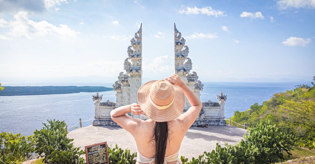 Woman in a sun hat enjoying the serene view from a Candi Bentar gateway in Bali, Indonesia.