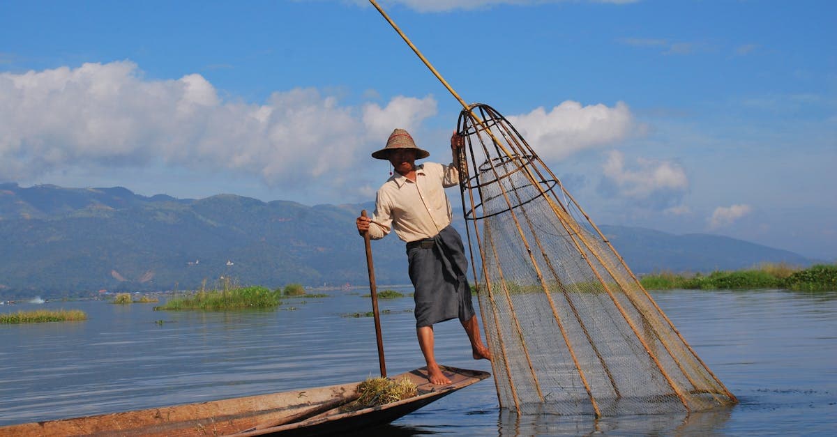Traditional Inle Lake fisherman balancing on his boat using a distinctive conical fishing net, Myanmar