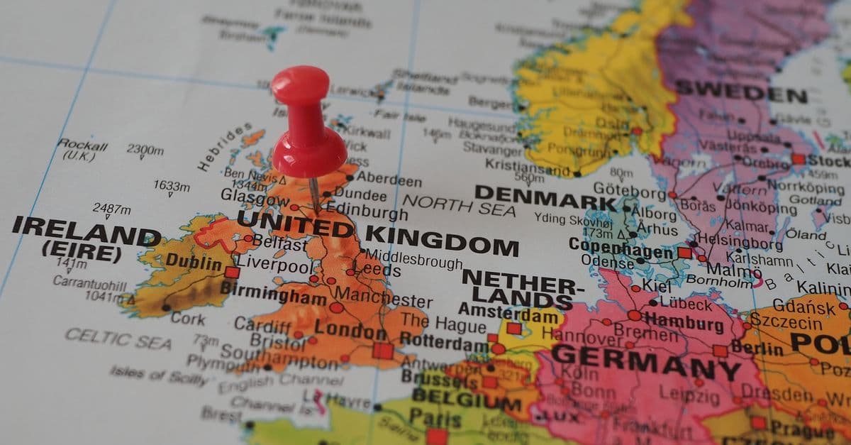 Close-up European map with a red pin marking a high-alert travel advisory destination in the UK.