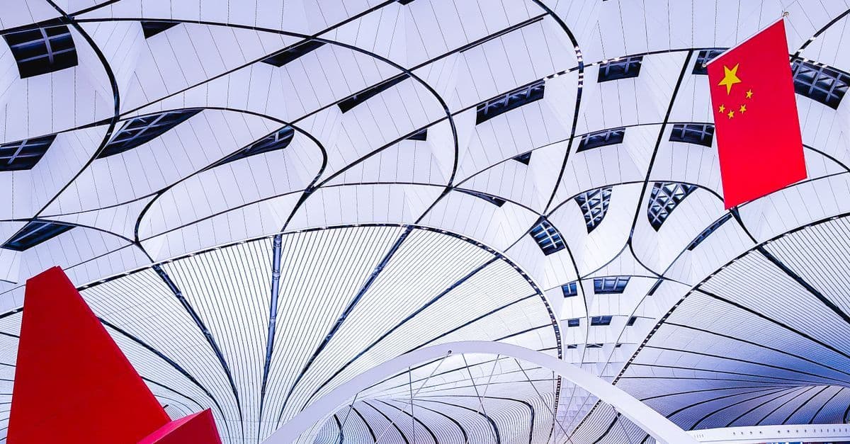 A Chinese flag hangs beneath the curved white roof of the terminal at Beijing Daxing International Airport.