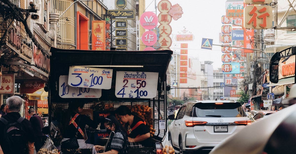 Belebter Straßenmarkt in Bangkok mit bunten Leuchtschildern und dichtem Verkehr, typisch für den Thailand Urlaub