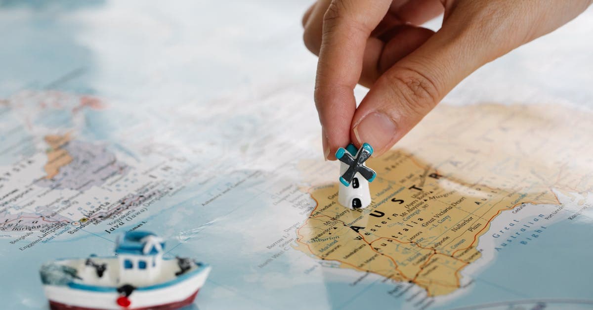 Hand placing a miniature windmill on a map highlighting Australia, choosing the best international roaming plan by destination