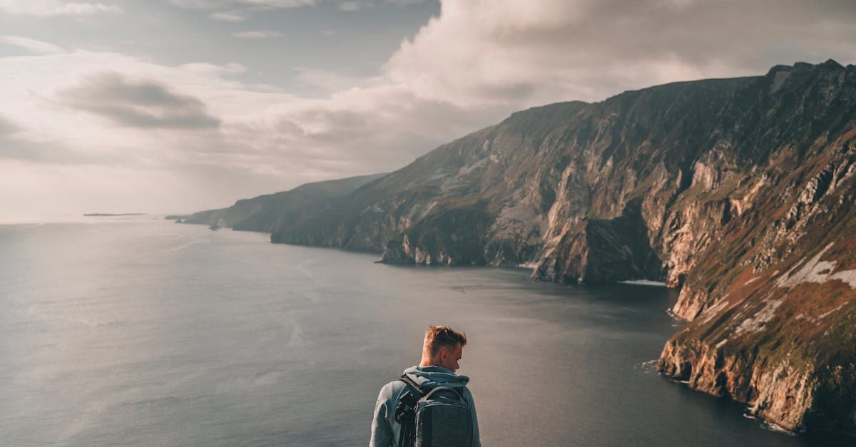 Traveller on Ireland's rugged coastal cliffs planning the budget for solo travel in Europe