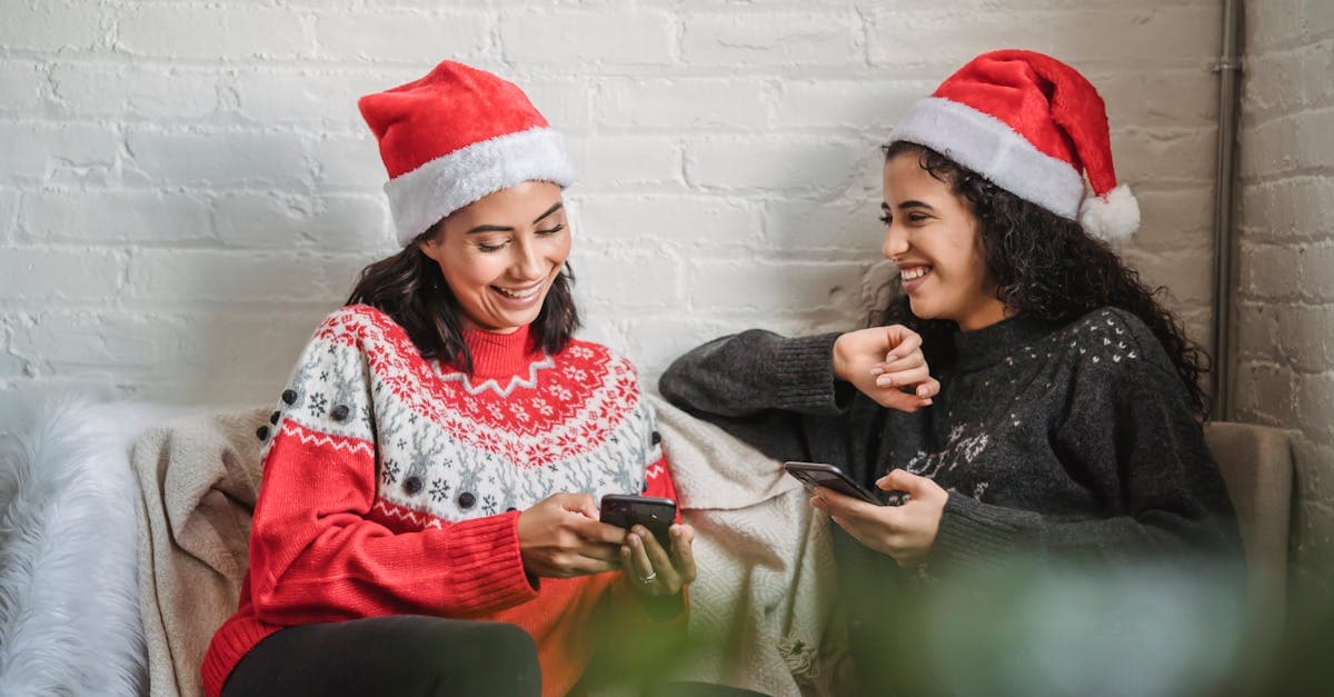 Two women in festive sweaters and Santa hats using smartphones to stay connected while traveling Europe in December