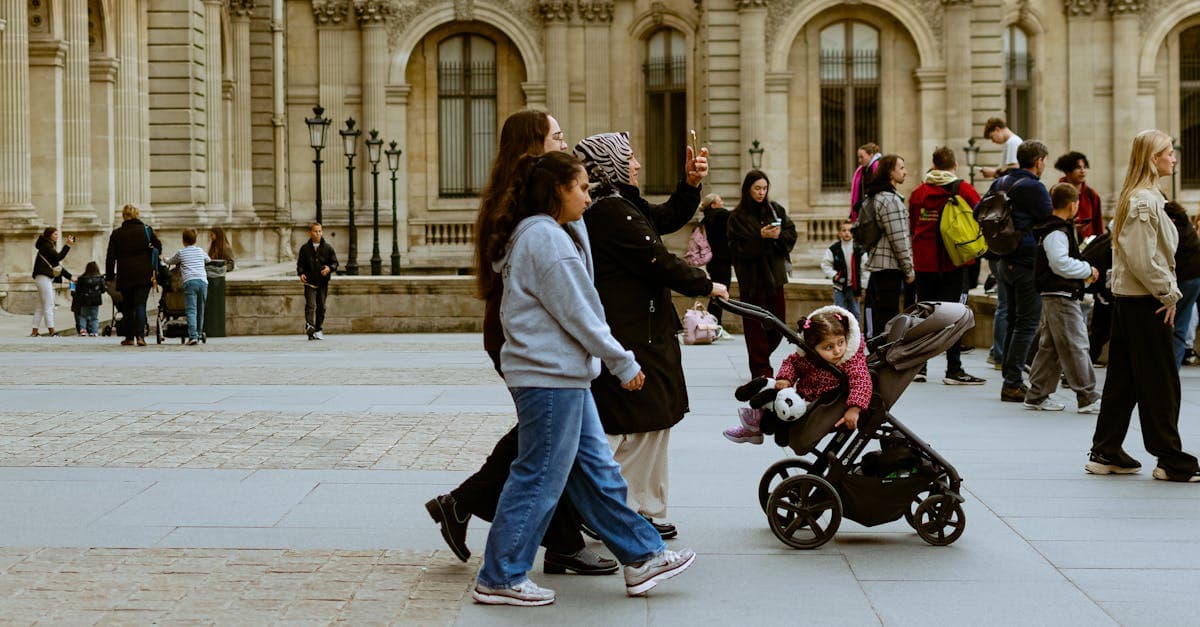 UK families with travel strollers navigate the bustling crowds outside the Louvre Museum in Paris