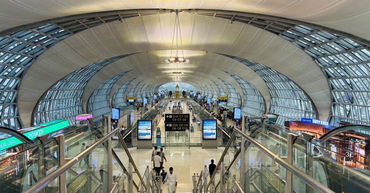 Hành khách kết nối internet tại sân bay Don Mueang với kiến trúc hiện đại xung quanh.