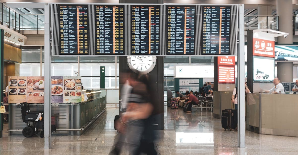 Rejsende i travl lufthavnsterminal med afgangstavler og stort ur på vej til gate