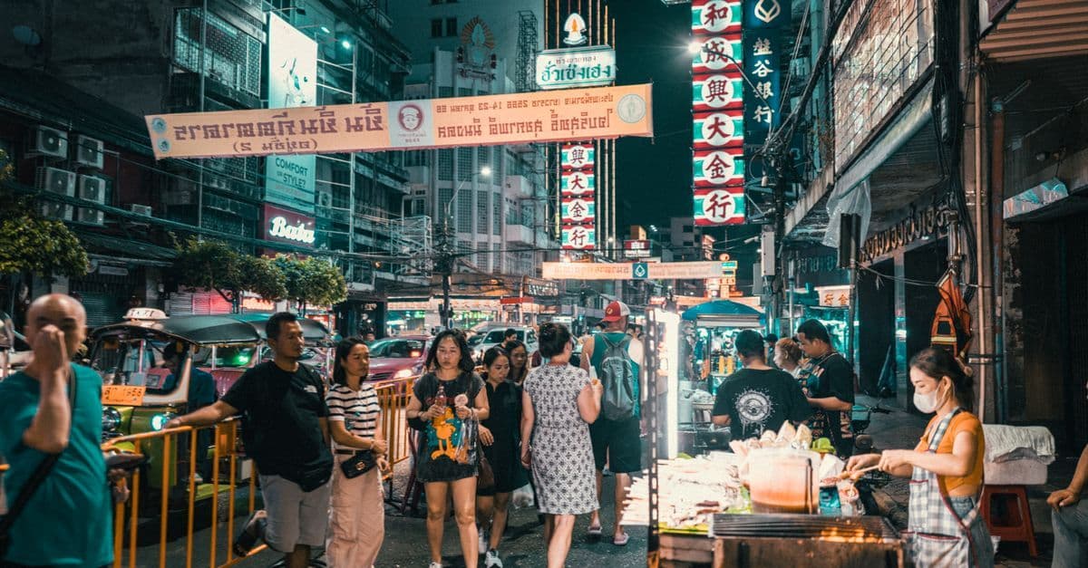 Geschäftiger Nachtmarkt mit Neonlichtern und Menschenmassen – idealer Ort für Bangkok Streetfood Entdeckungen.