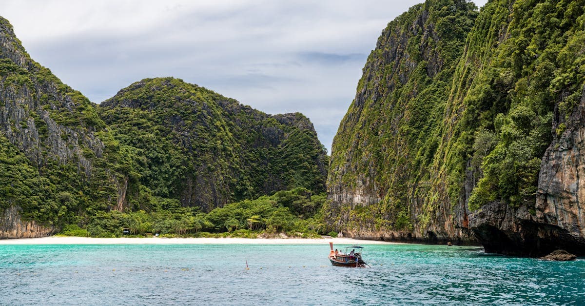 Traditionelles Boot vor Kalksteinfelsen und türkisem Wasser am Long Beach auf Koh Phi.