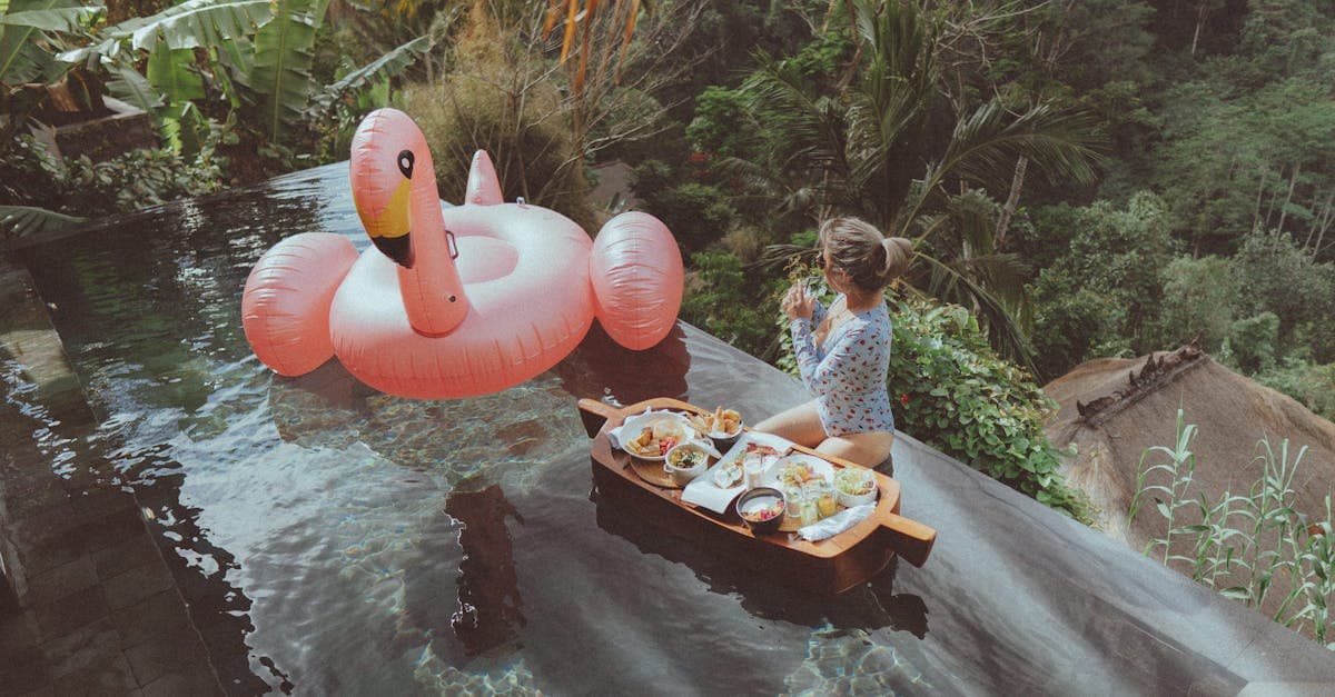 Woman enjoying breakfast in an infinity pool with a flamingo float at a Bali resort. Tropical serenity and relaxation.