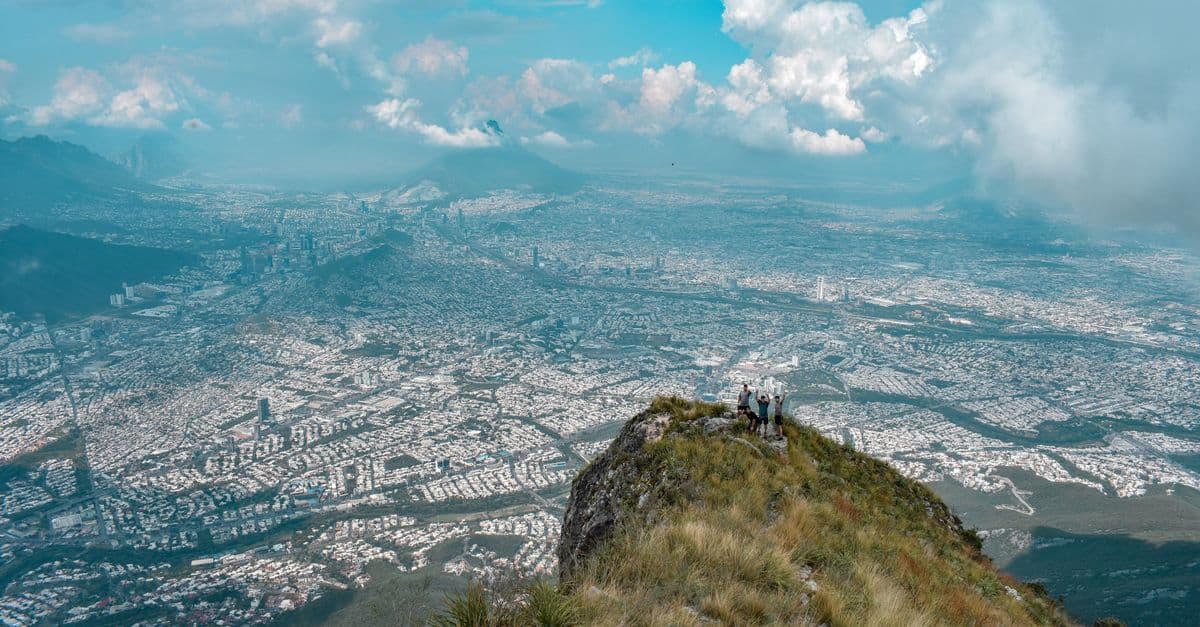 Sweeping aerial view of Monterrey Mexico's sprawling urban landscape seen from a dramatic mountain peak.