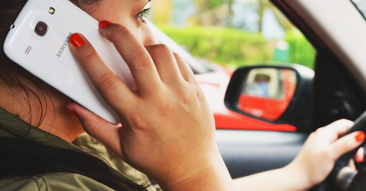 Close-up of a woman driving a car while talking on a smartphone, highlighting road safety concerns.