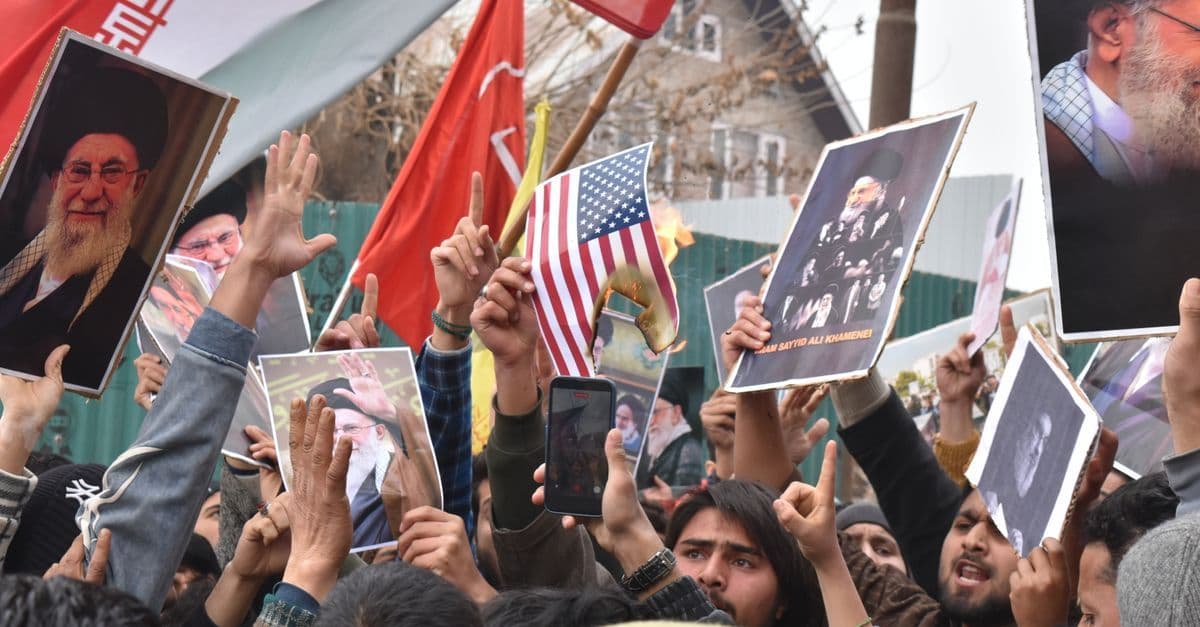 Demonstranten mit Fahnen und Transparenten protestieren gegen den Krieg USA Iran auf der Straße