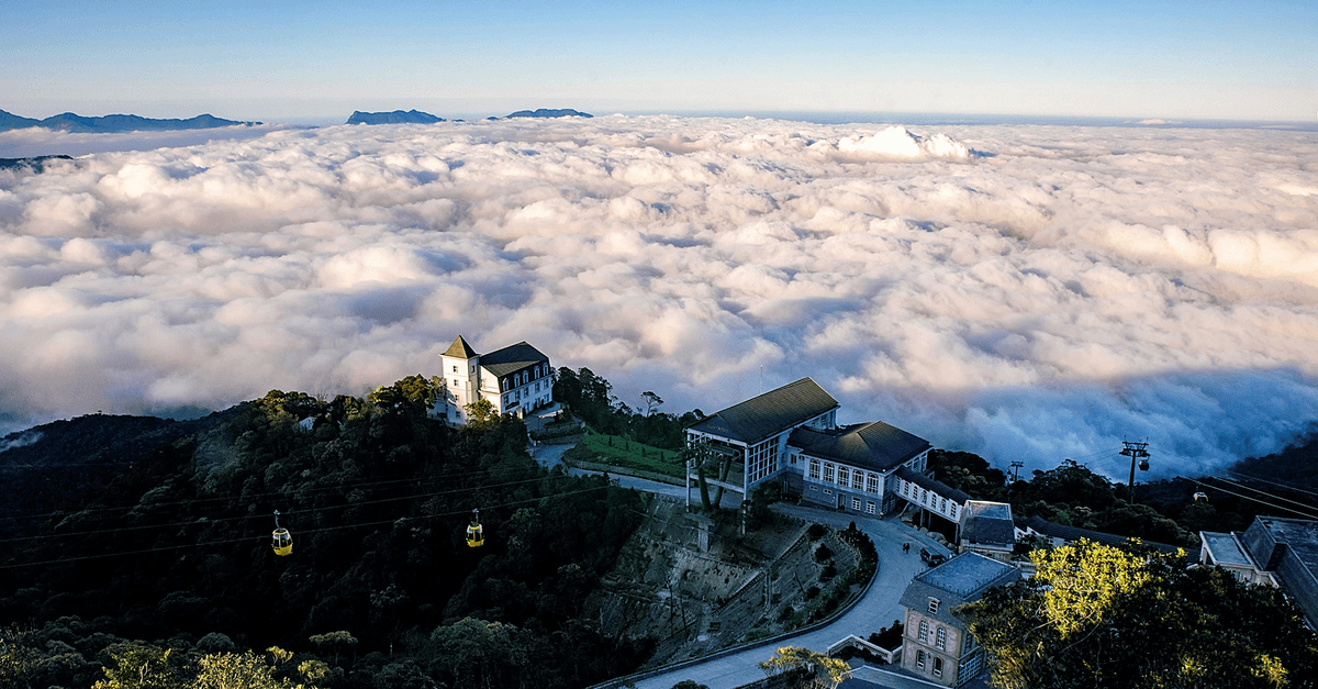 山頂建築群與纜車俯瞰翻湧雲海,遠方山脈露出雲層,天空晴朗。