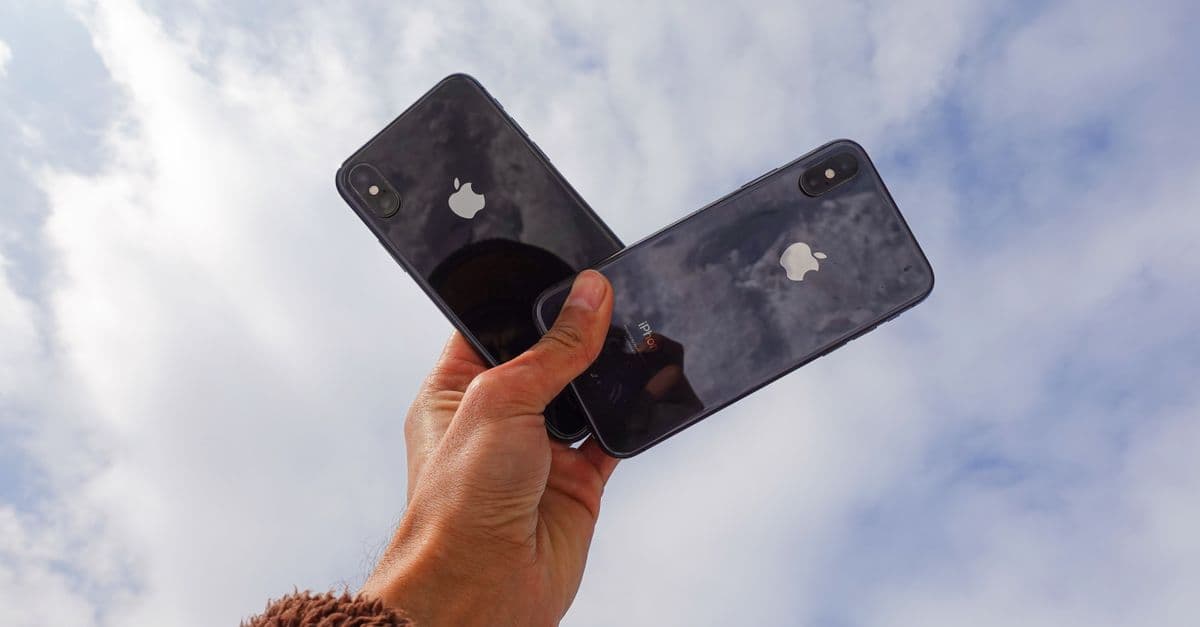 Dos smartphones sostenidos bajo el cielo, ilustrando cómo rastrear iPhone con la función Find My