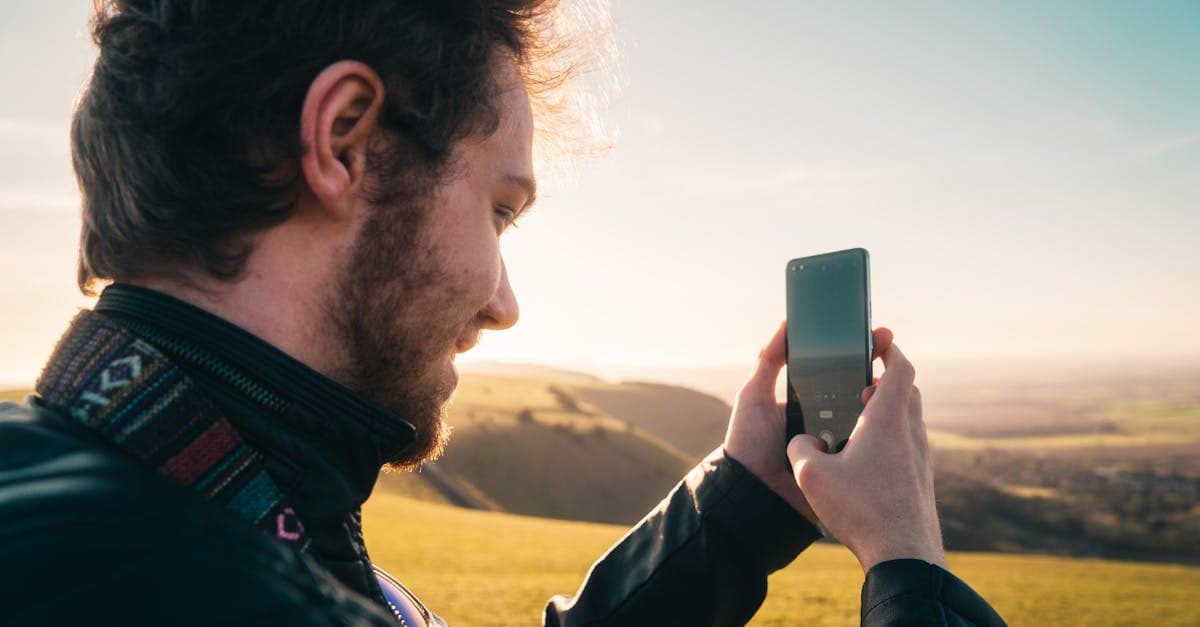 Man photographing a scenic coastal landscape with a smartphone, staying connected in America with a travel eSIM.