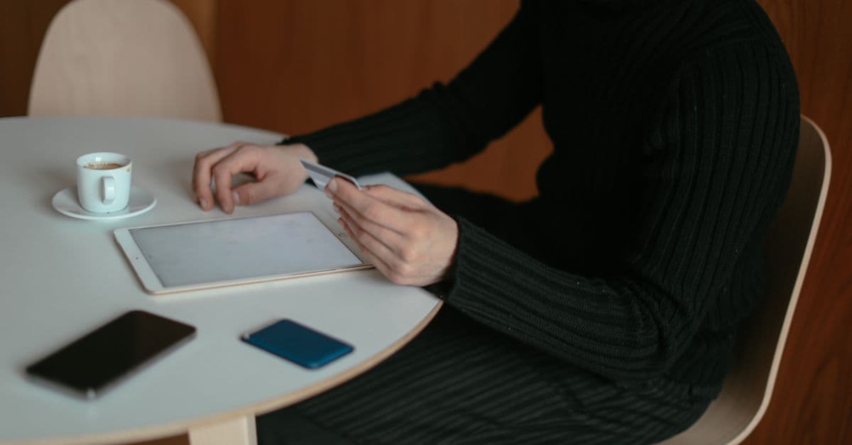 Uomo che effettua acquisti online con tablet e carta di credito grazie a una connessione eSIM condivisa.