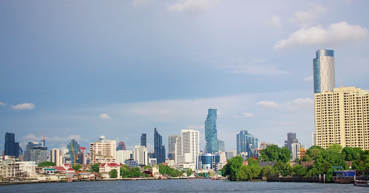 Bangkoks moderna skyline med skyskrapor och flod badar i solsken.