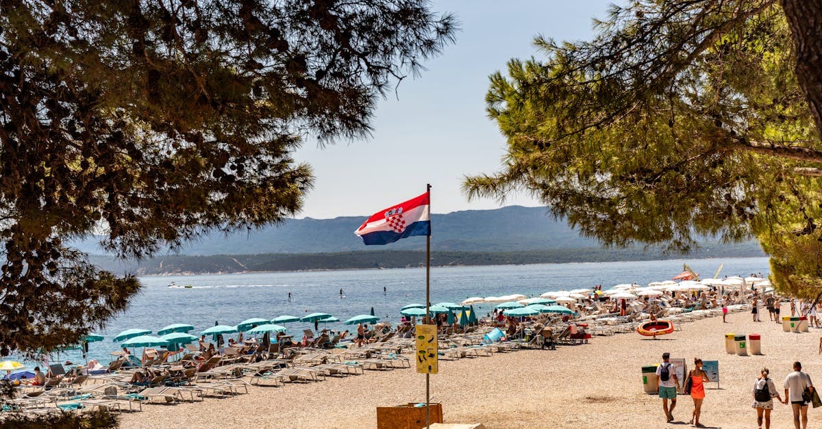 Zlatni Rat-stranden med kristallklart blått vatten och solbadande turister på sommaren