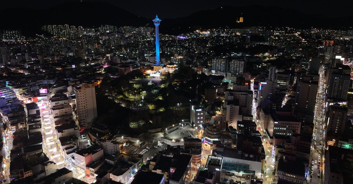 釜山の象徴的なタワーと輝く街並みの夜景空撮、韓国eSIMおすすめの通信品質が安定した主要都市