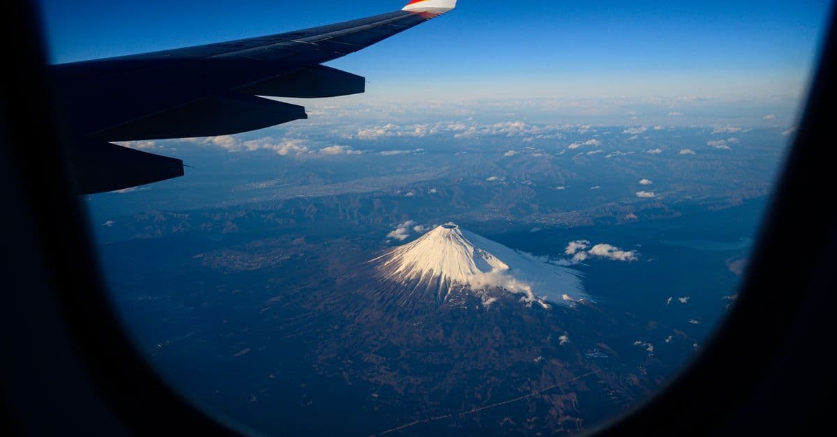 Iconic snow-capped Mount Fuji seen from an airplane window on a return flight to Japan.