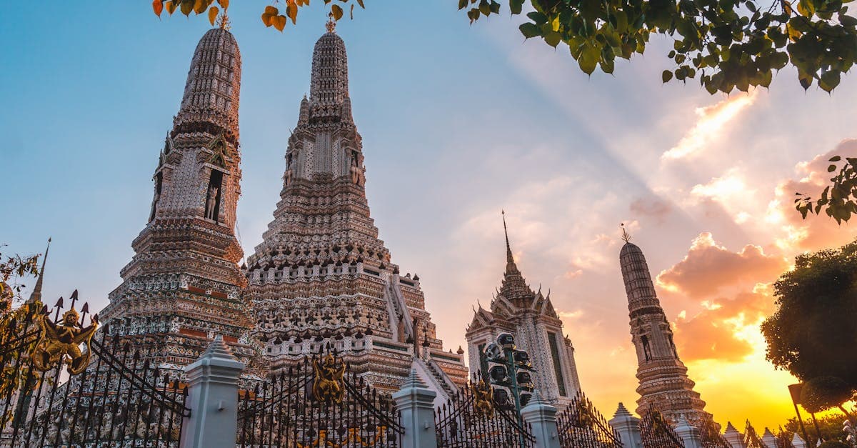 Vibrant sunset casting a warm glow over Wat Arun's ornate spires in Bangkok, Thailand.