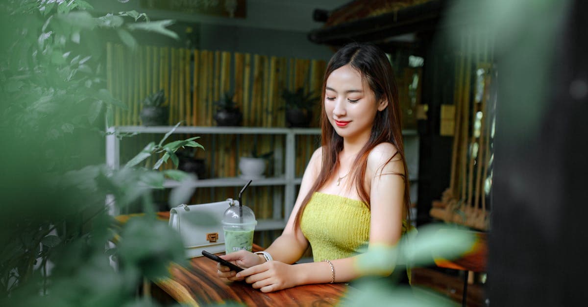 Young woman on her smartphone in a plant-filled Bali café, staying connected while discovering the island