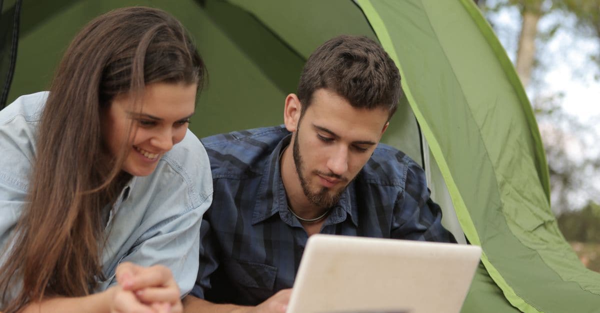 Stel surft op laptop in het park met tijdelijk mobiel internet als alternatief voor KPN.