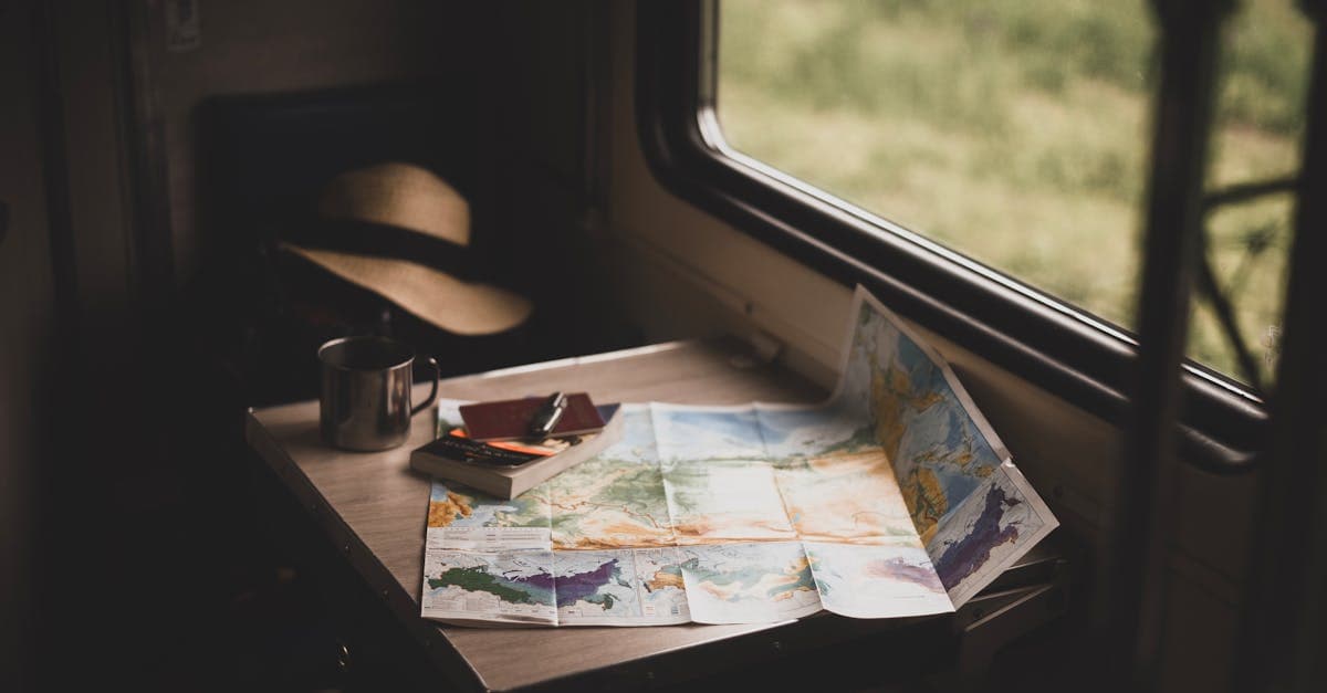World map, travel mug, and hat on a train table while planning a 10 or 16-day japan itinerary
