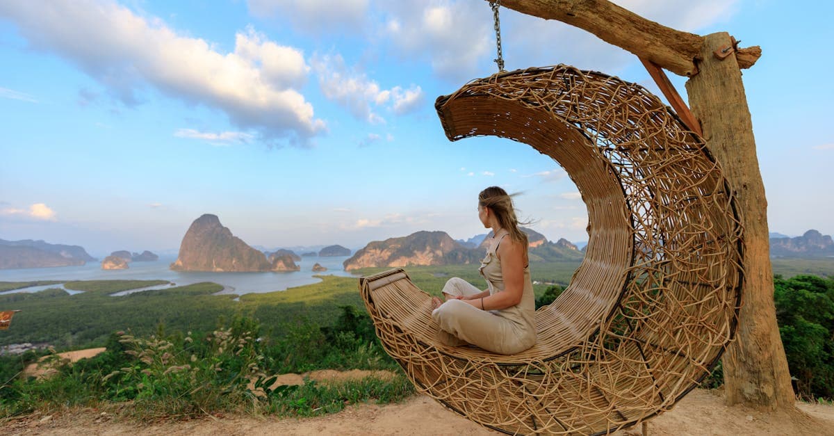 Vrouw in rieten hangmat geniet van het panoramisch uitzicht over de Phang-nga Baai bij zonsondergang in Thailand.