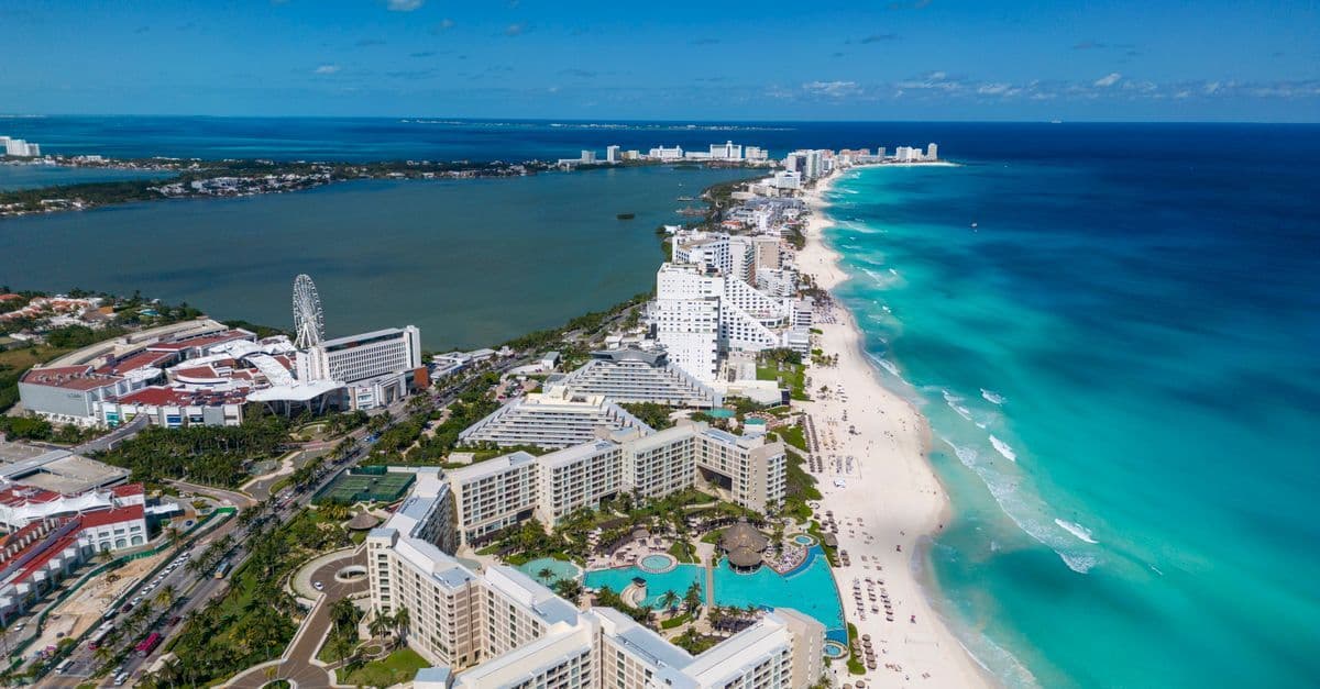 Aerial view of Cancun's hotel zone, with resort buildings between a turquoise beach and a broad lagoon.