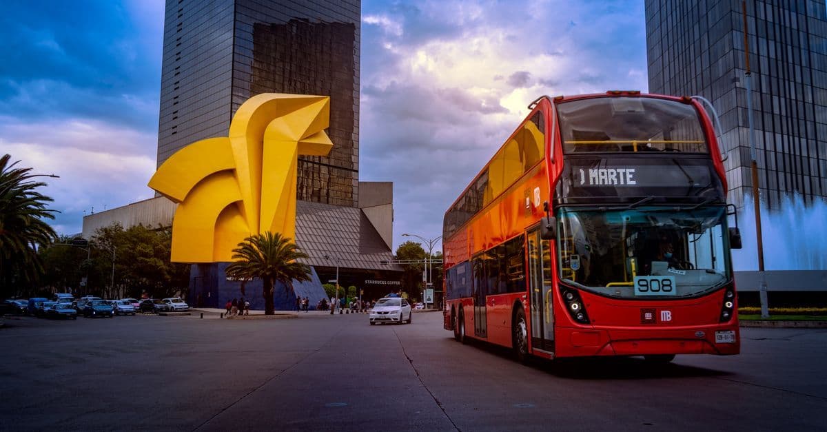 Autobús de dos pisos frente a El Caballito en CDMX, ruta de transporte hacia Pachuca desde la capital.