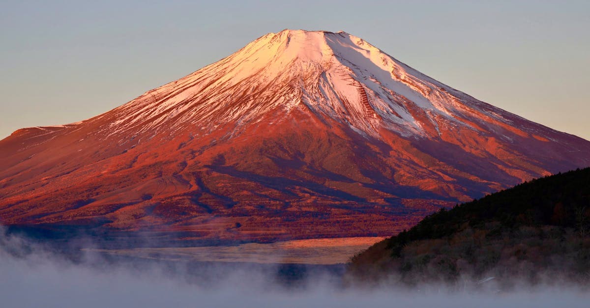 Snow-capped Mount Fuji at sunrise with mist, one of the top natural things to do in Japan