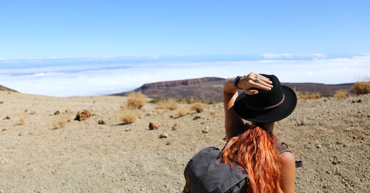 Woman in a hat and backpack gazing at desert mountains, proving solo travel has no age limit.
